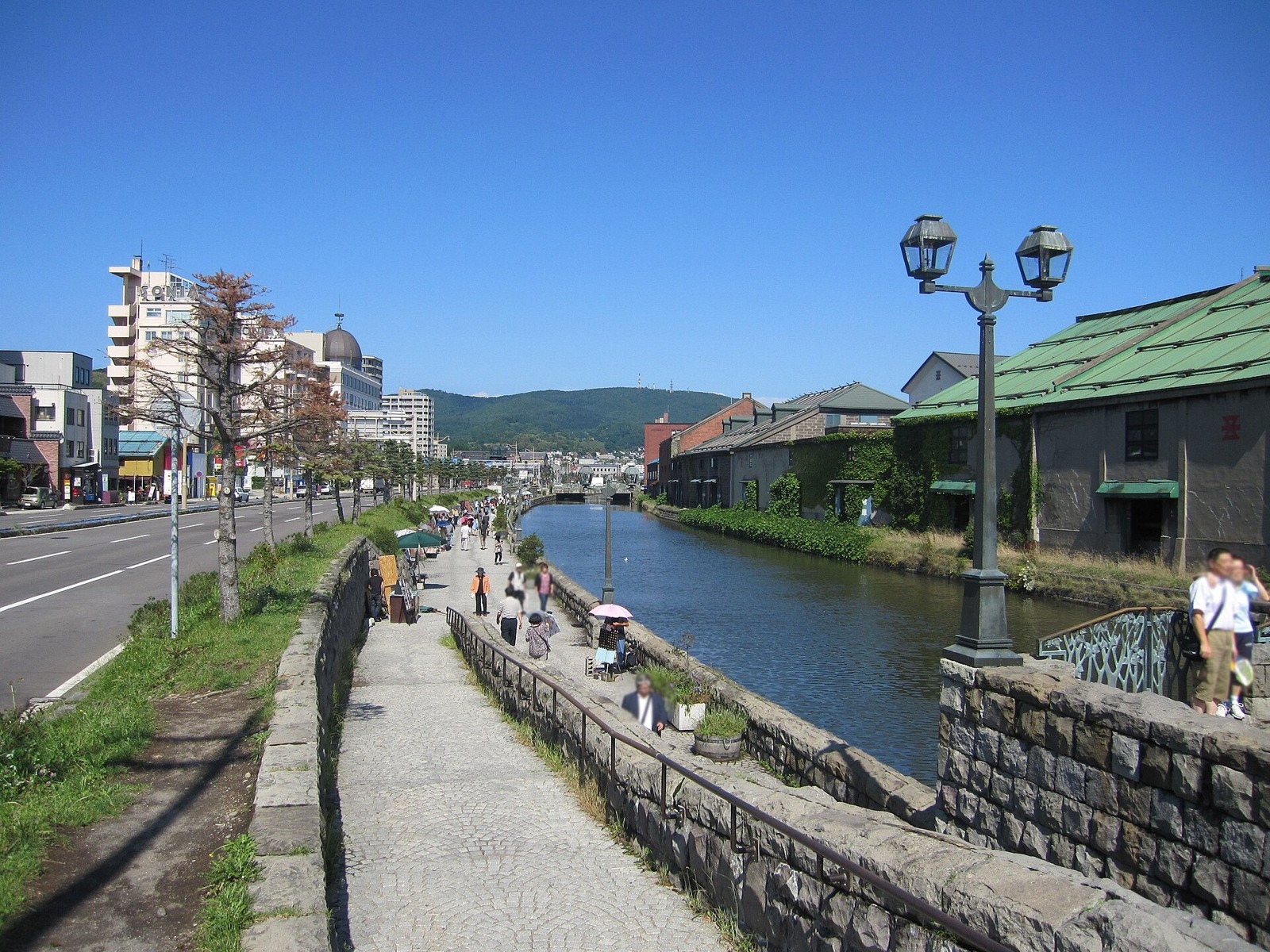 The canal’s stone walkway and lamps in summer daylight.