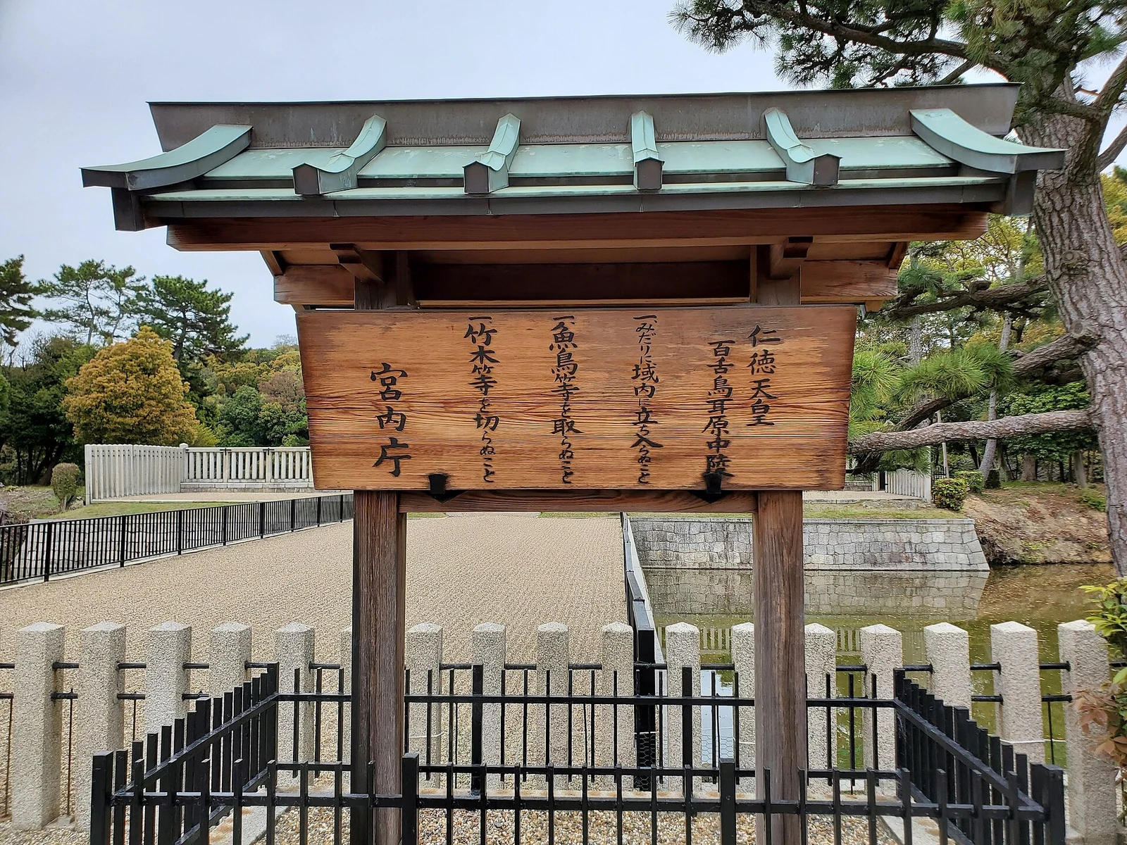 A sign and outer gate at the tomb in April 2024.