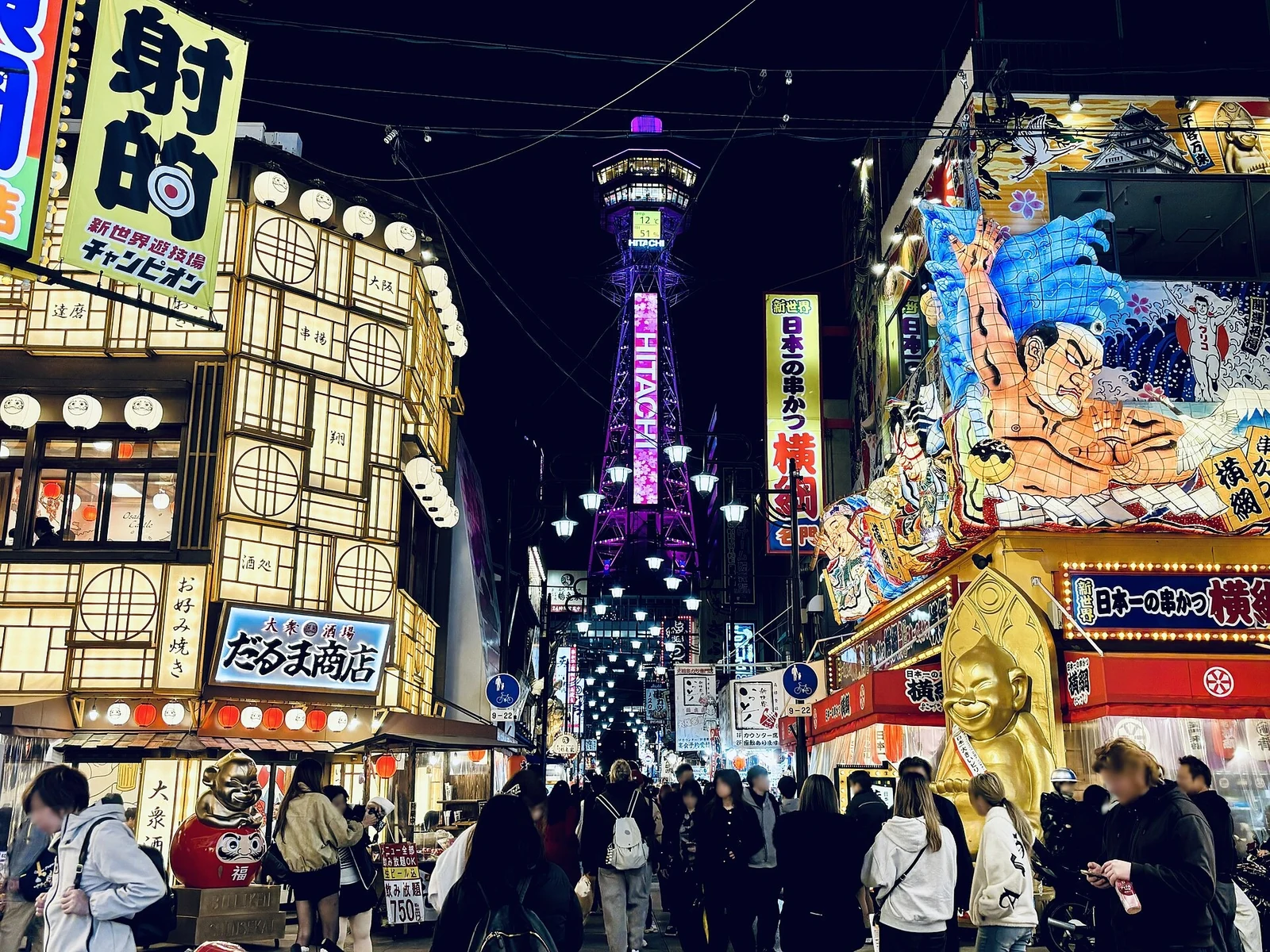 Tsutenkaku and Shinsekai’s illuminated street at night.