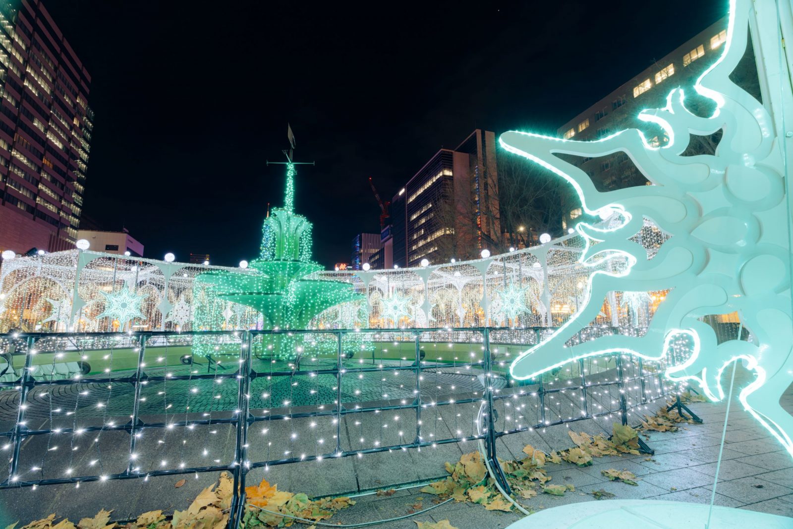 A large glowing snowflake in the foreground, with white passage lights and a green central installation behind it.