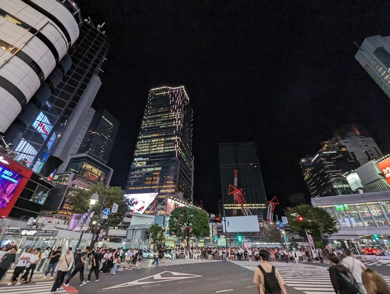 Shibuya Scramble Crossing at night, beneath the surrounding city lights.